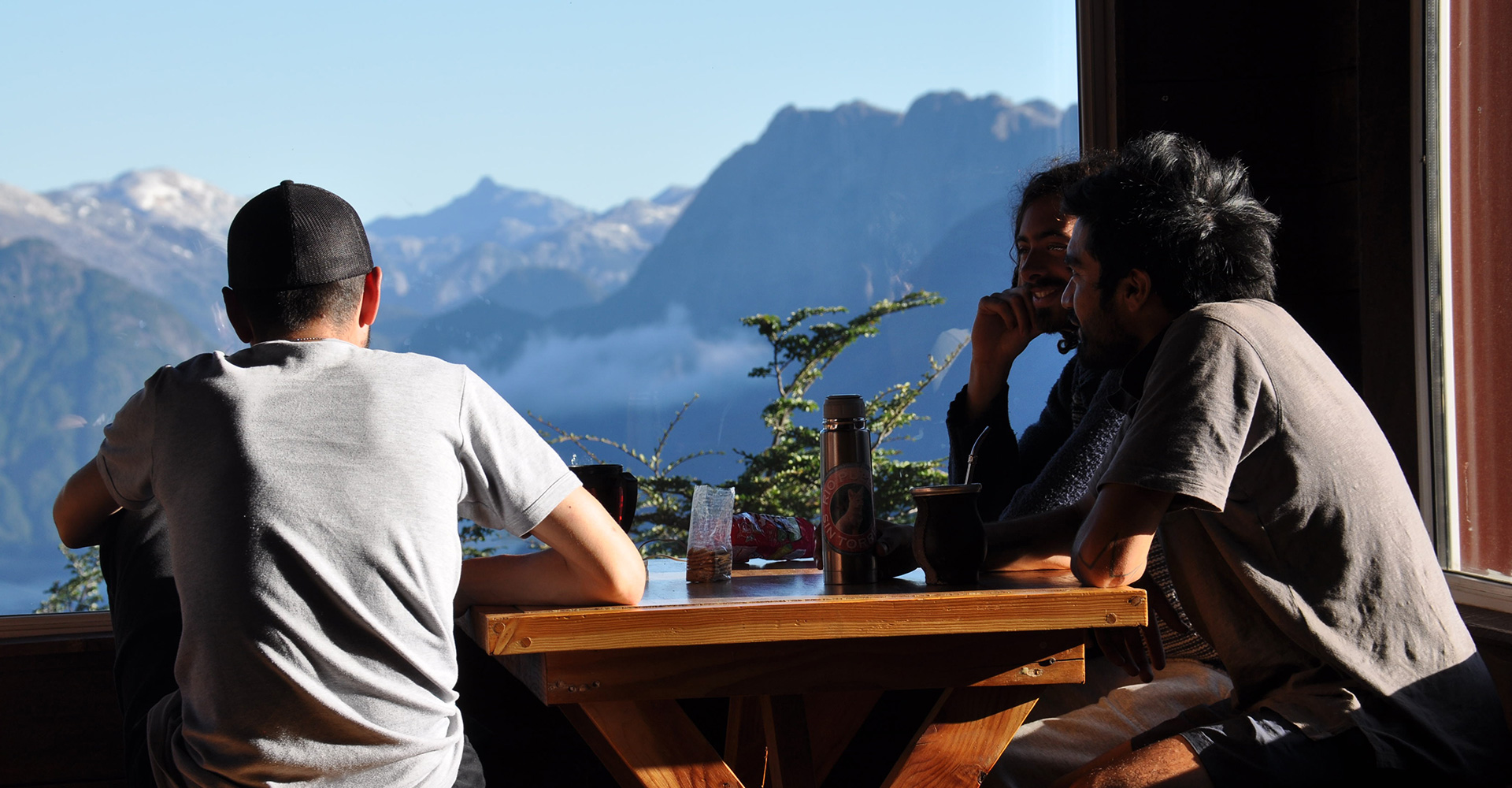 Interior cálido del refugio con mesas de madera listas para recibir visitantes.